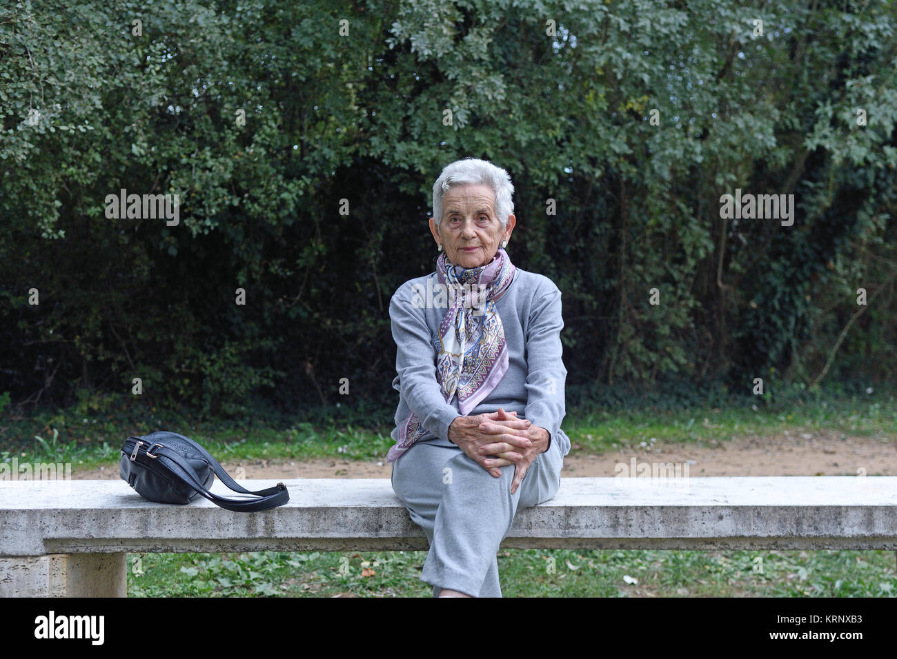 senior woman sitting alone on a bench in a park Stock Photo - Alamy