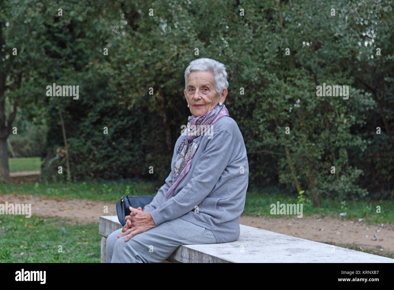 senior woman sitting alone on a bench in a park Stock Photo - Alamy