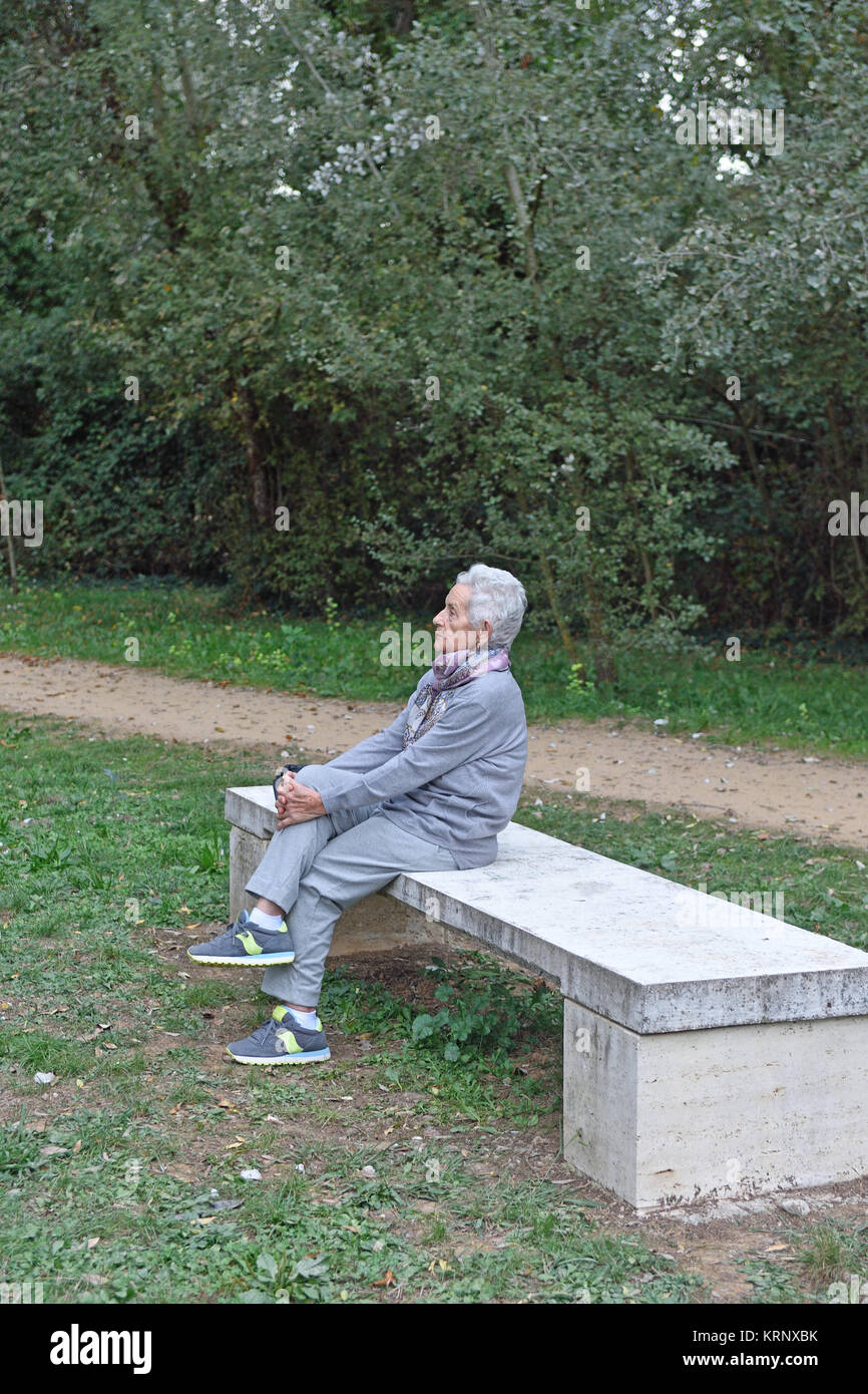senior woman sitting alone on a bench in a park Stock Photo - Alamy