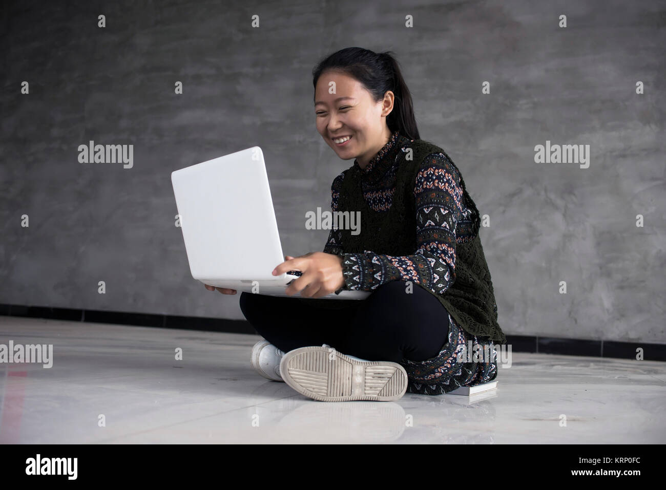 Woman sitting on the floor holding a laptop and smiling Stock Photo - Alamy