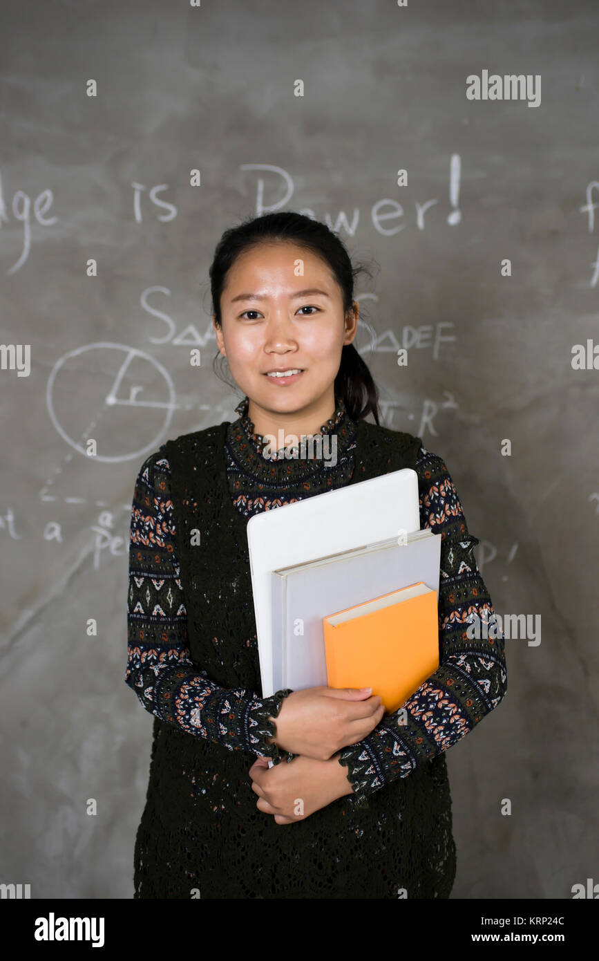 Confident female college students stand in front of the blackboard. Stock Photo