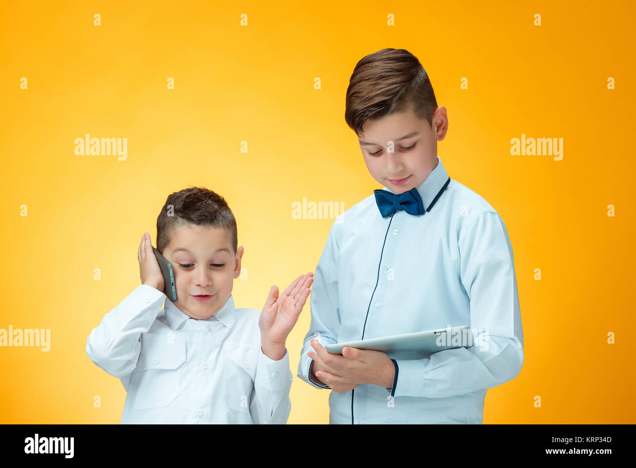 The two boys using laptop on orange background Stock Photo - Alamy