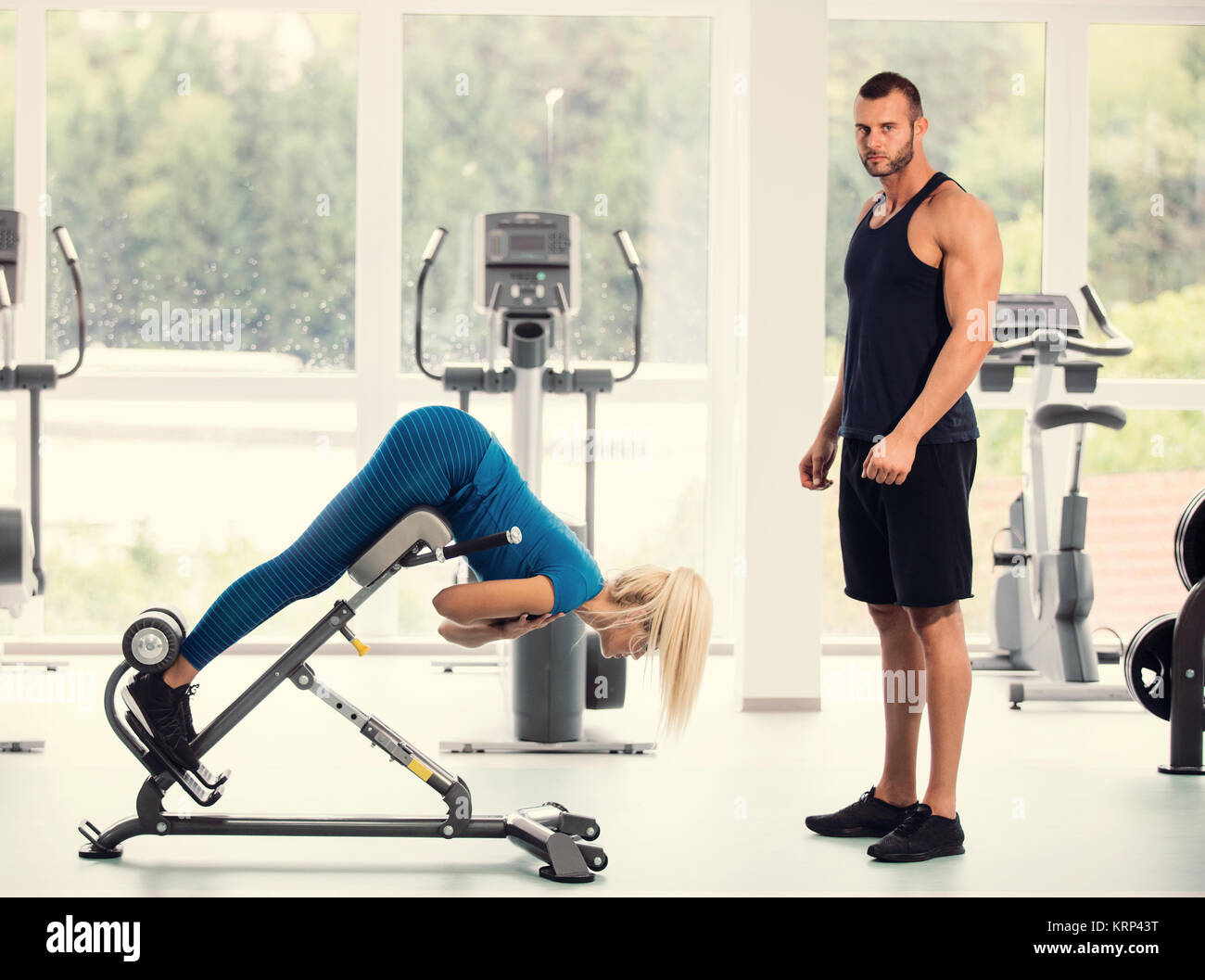 Attractive young sports people are talking and smiling while lying in gym Stock Photo