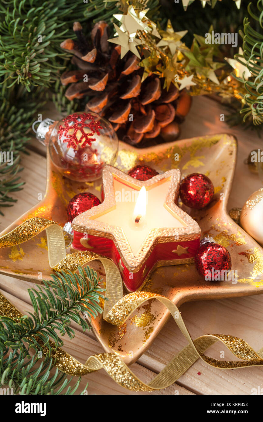 Kleine brennende Kerze mit Weihnachtsdekoration und Tannenzweige Stock