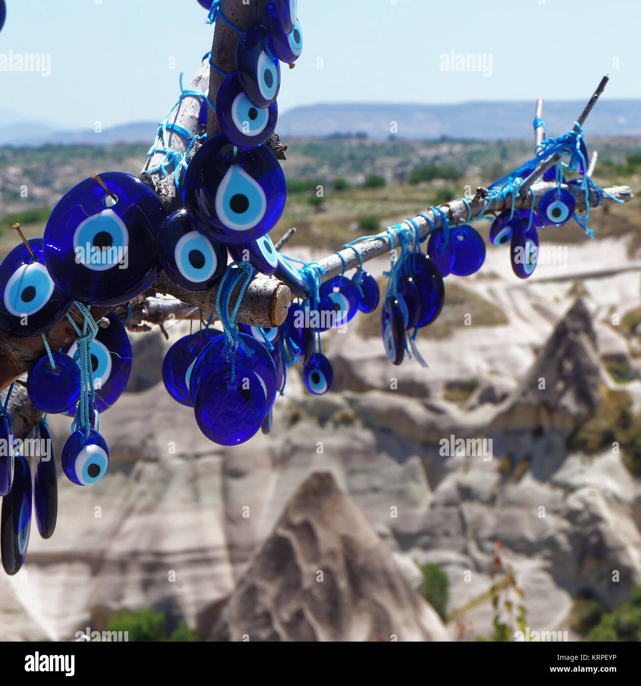 The blue glass eye (Nazar Boncugu) as a defence against the evil eye, at a branch in front of the mountains of Cappadocia, closeup Stock Photo