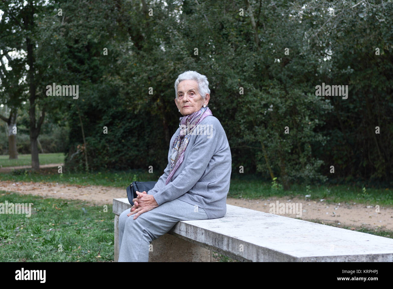 senior woman sitting alone on a bench in a park Stock Photo - Alamy