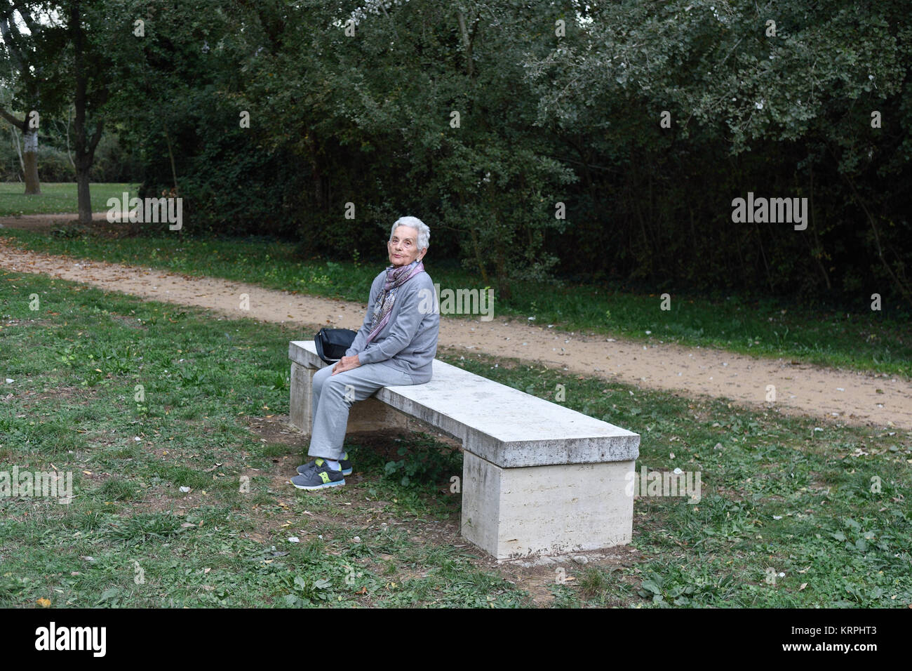 senior woman sitting alone on a bench in a park Stock Photo - Alamy
