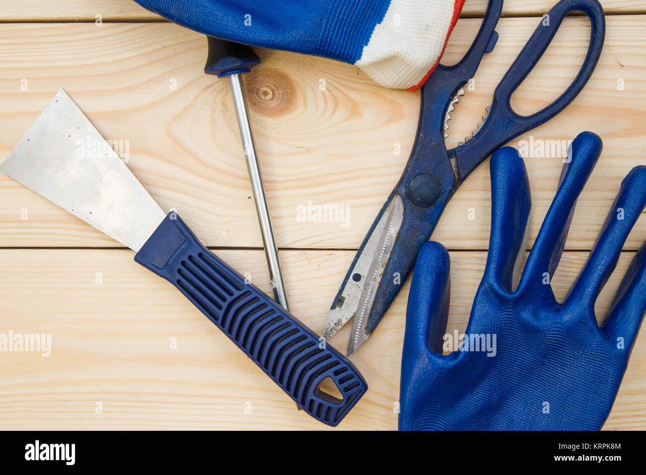 Repairing and construction concept. A set of tools -a plastering trowel, scissors, screwdriver and gloves on a light uncolored wooden background, clos Stock Photo
