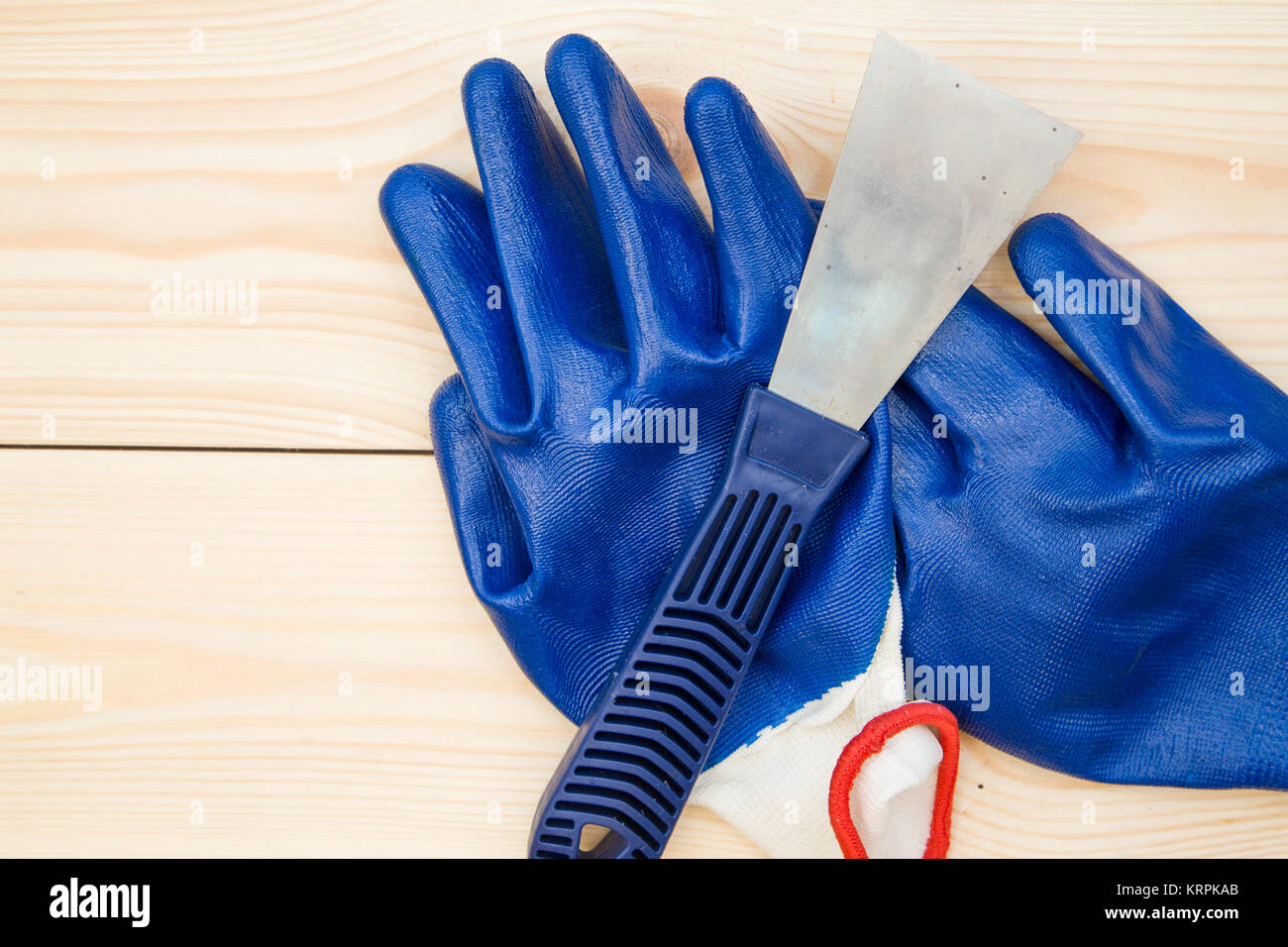 Repairing and construction concept. A plastering trowel and blue latex gloves on a light uncolored wooden background, close up. Top view. Space for yo Stock Photo
