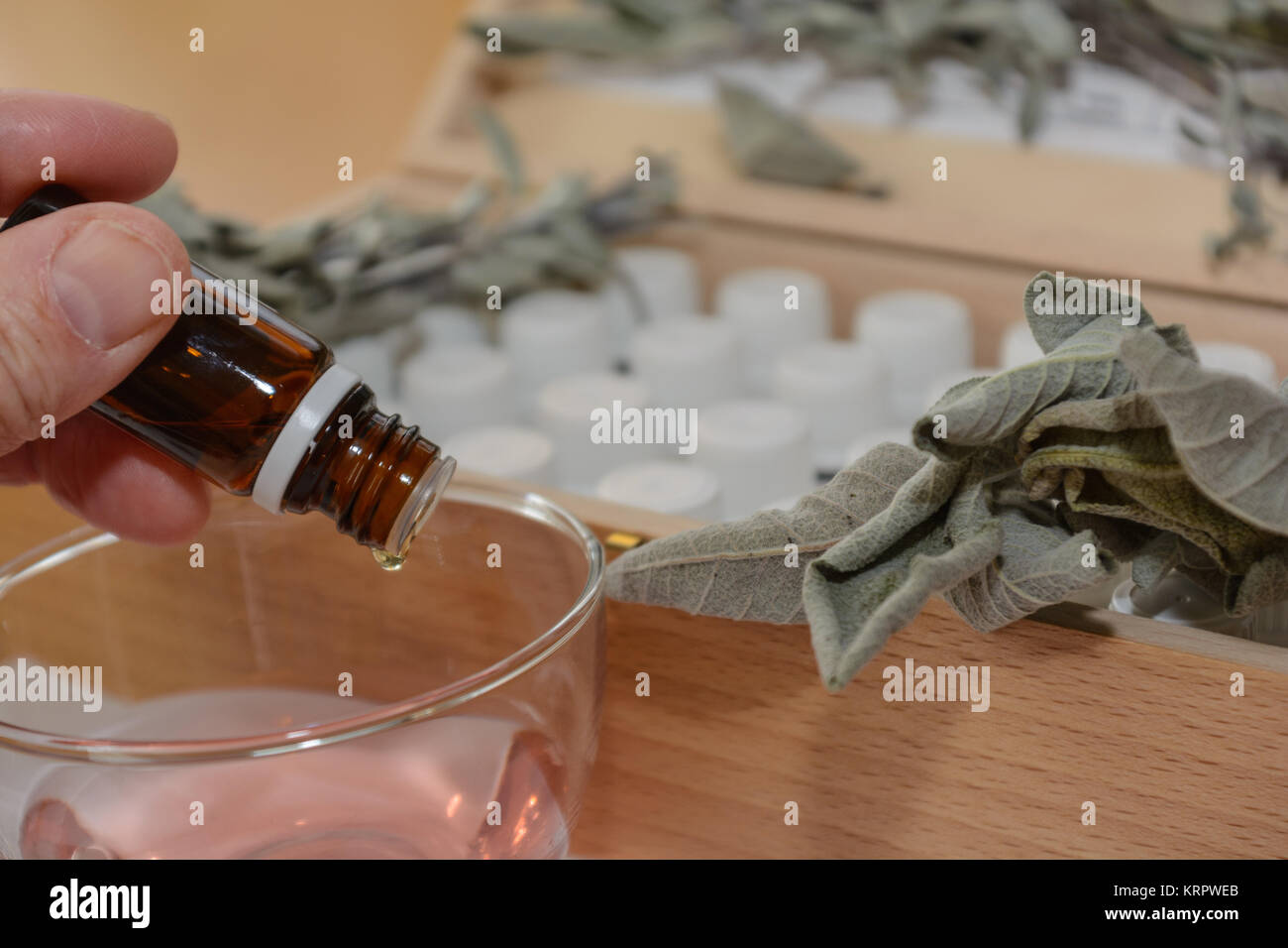 Aus braunem Glasfläschchen tropft etwas in eine andere Flüssigkeit - Nahaufnahme Stock Photo