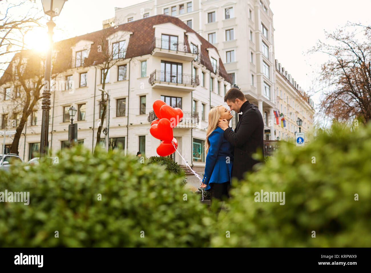 A young couple in a coat are holding a balloons heart in the cit Stock ...