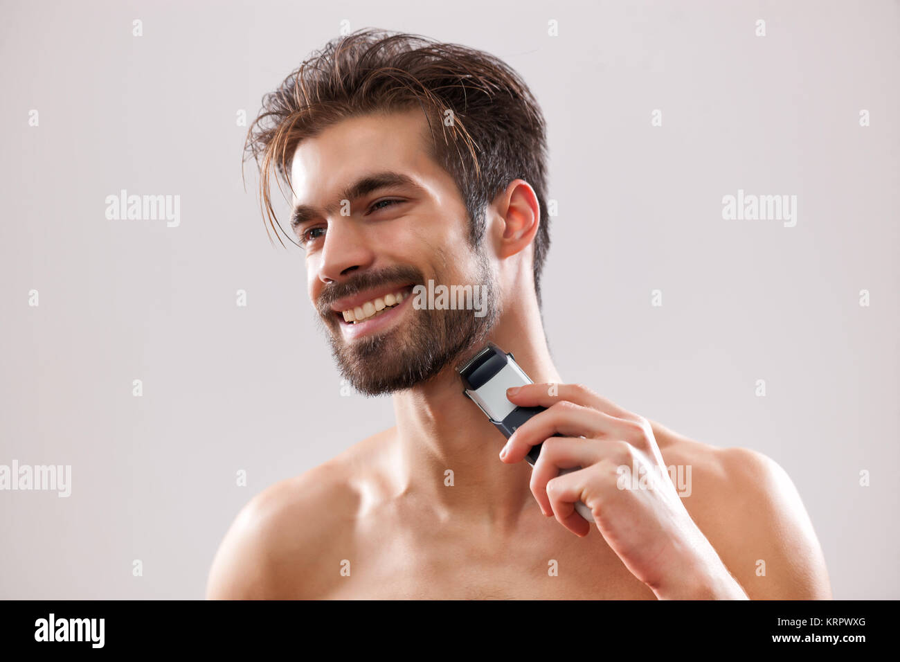 Young man is shaving his beard with electric razor Stock Photo Alamy