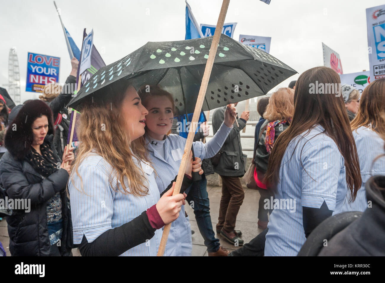 A short heavy shower makes some marchers put up umbrellas on the march to save NHS Student Bursaries. Stock Photo