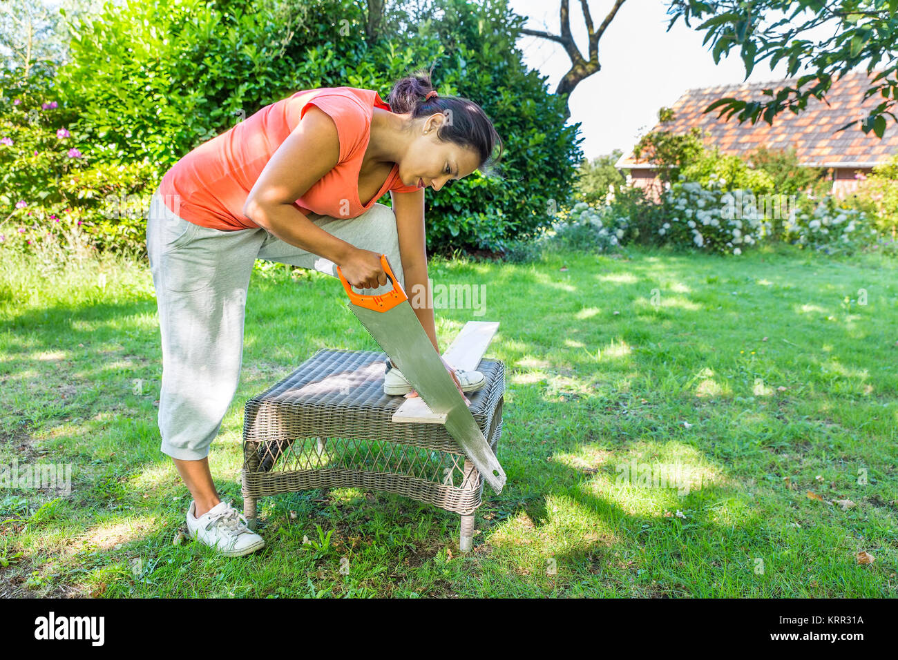 Young colombian woman sawing wood with handsaw outdoor Stock Photo