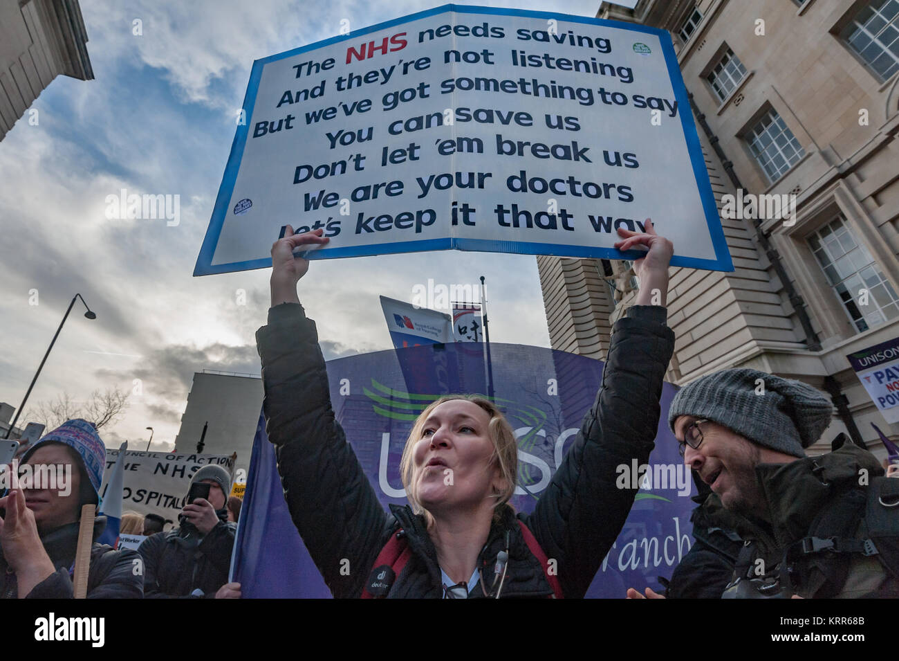 A Junior Doctor holds up the words as the National Health Singers perform before the march to save NHS Student Bursaries. Stock Photo