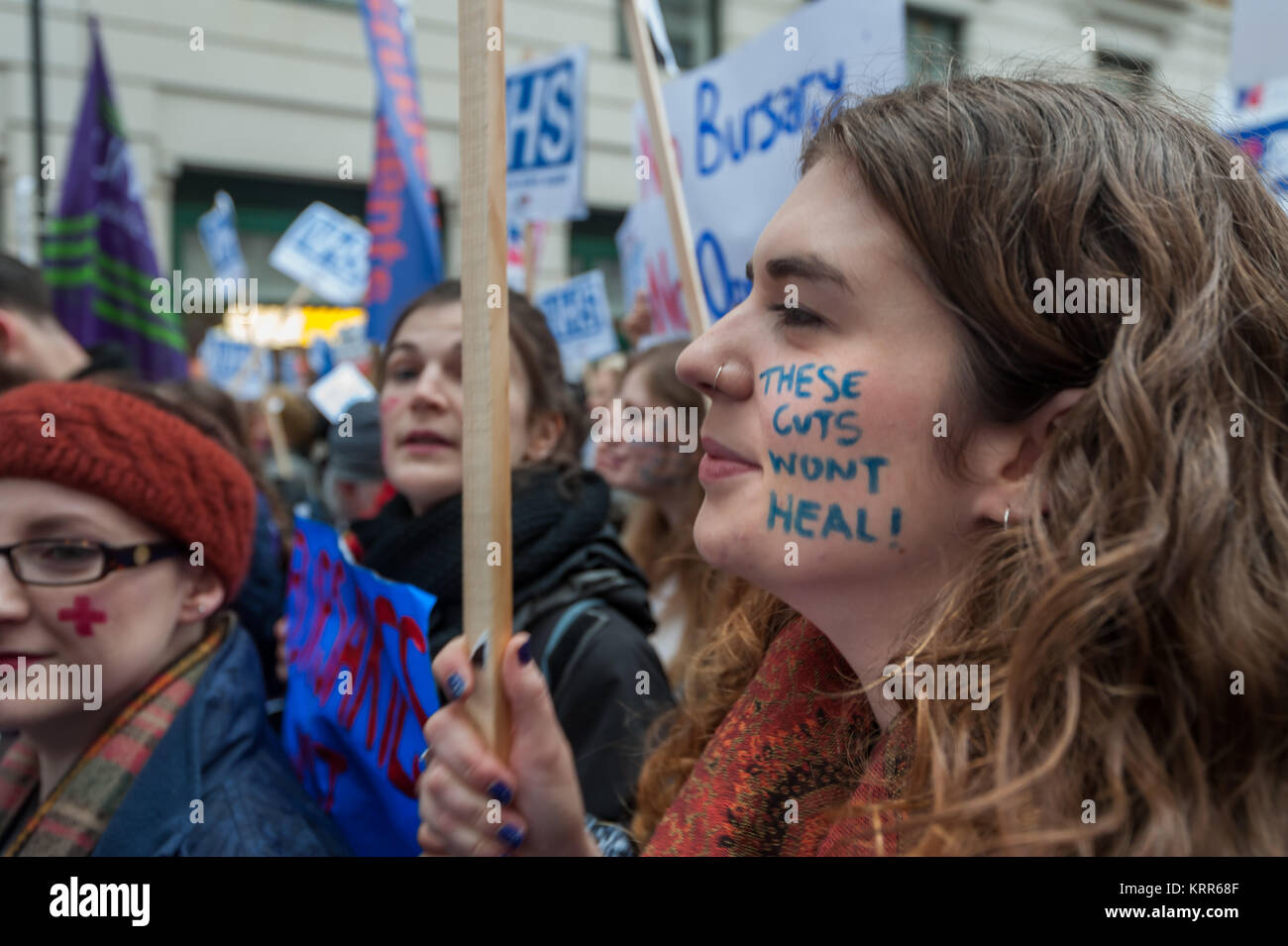 A woman in the crowd has 'These cuts wont Heal!' on her face before the march to save NHS Student Bursaries. Stock Photo