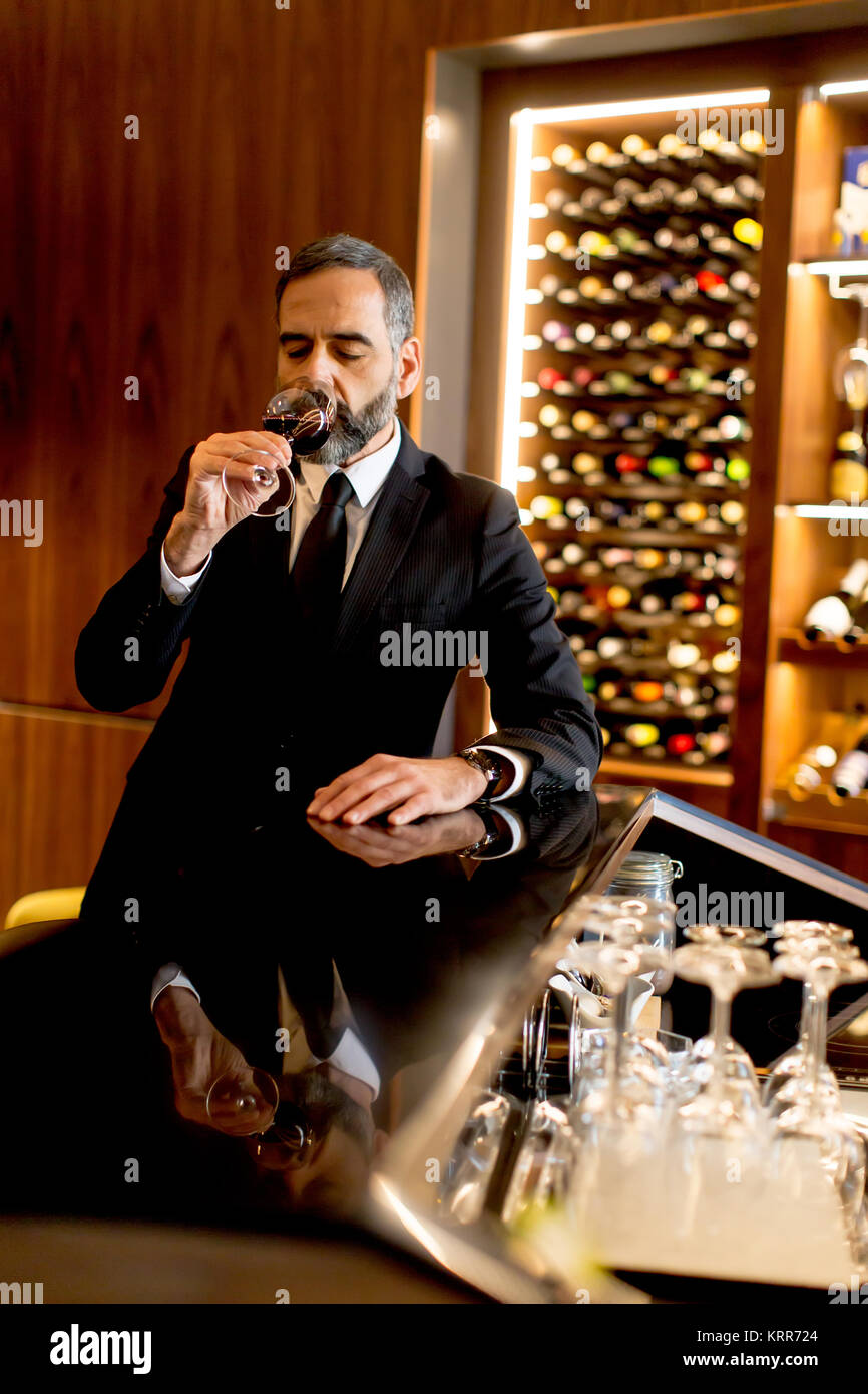 Handsome mature man tasting glass of red wine Stock Photo - Alamy