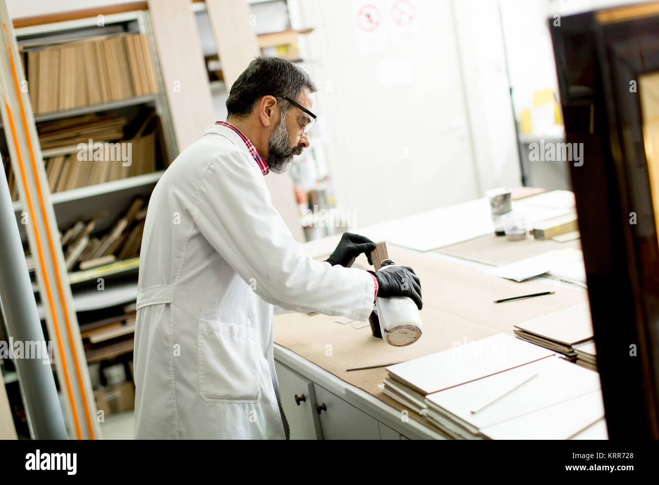 Handsome mature engineer testing colors on wooden specimens in the