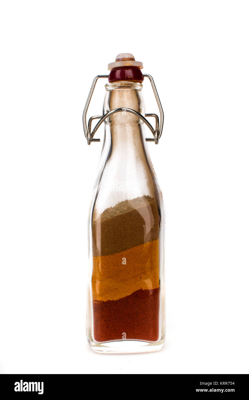 A glass jar/container holding different types of spices, such as nutmeg, cinnamon and mixed herbs for cooking Stock Photo