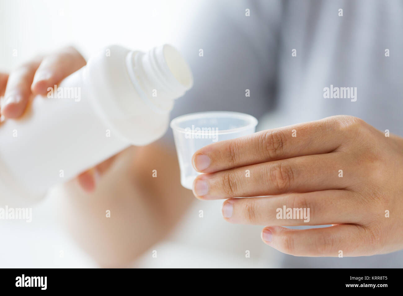 woman pouring syrup from bottle to medicine cup Stock Photo Alamy