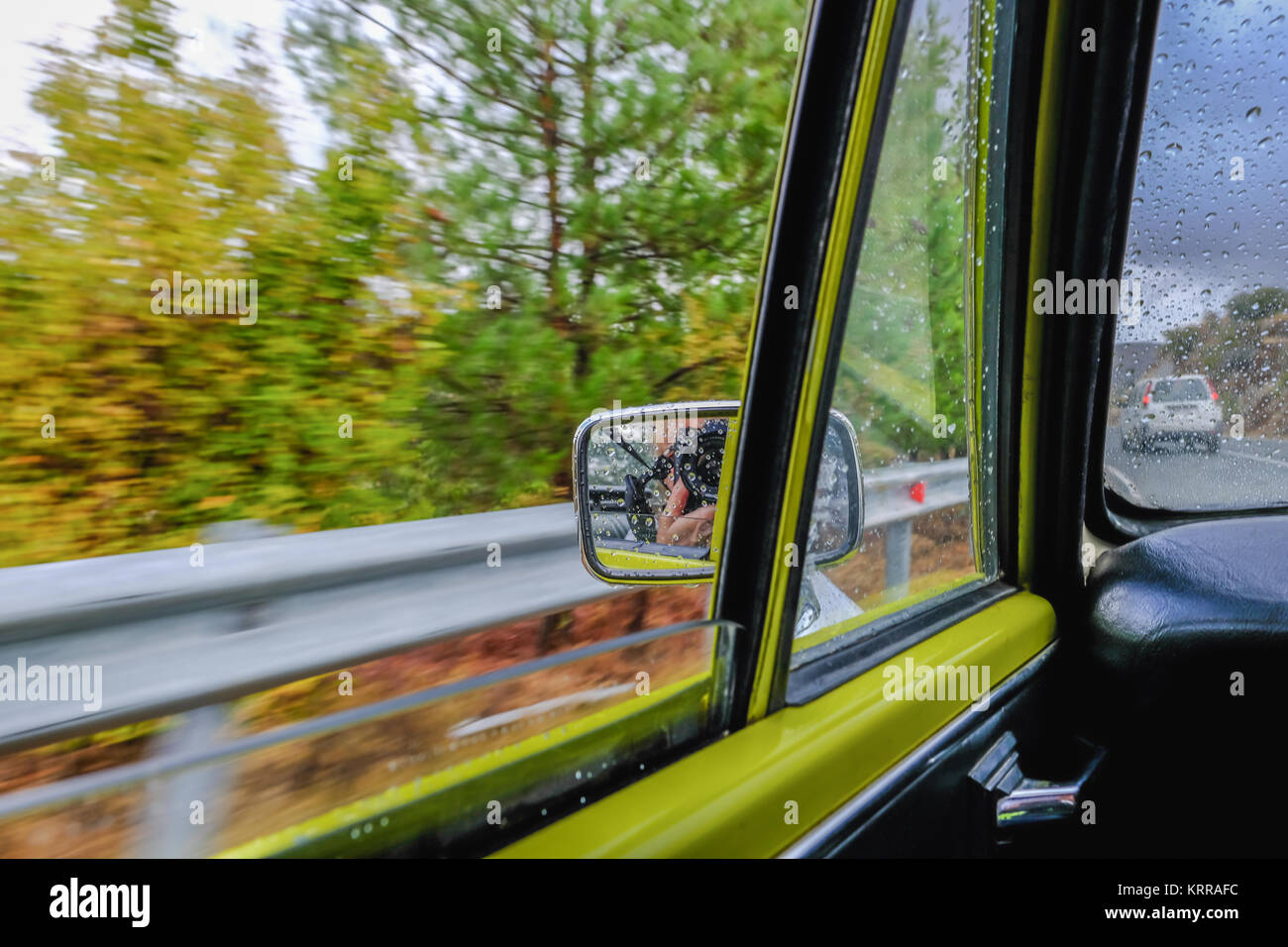 Looking out of the window of this vintage car as it travels along the motorway.  Shows motion in side miiror view. Stock Photo