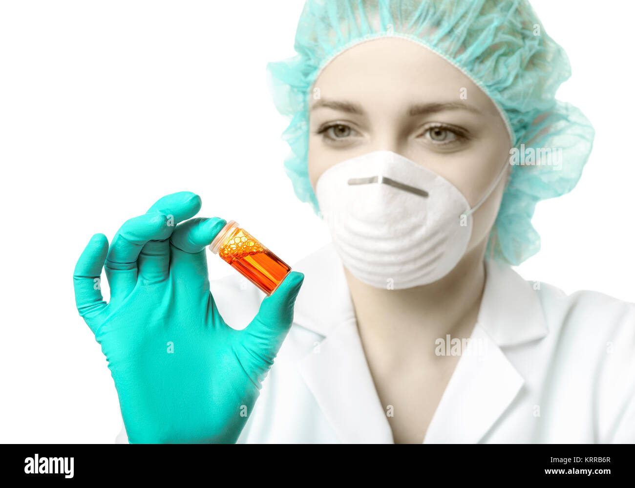 Female scientist or tech in lab coat, gloves and hat holds liquid biological sample. This image is isolated on white. Shallow DOF, focus on the tube a Stock Photo