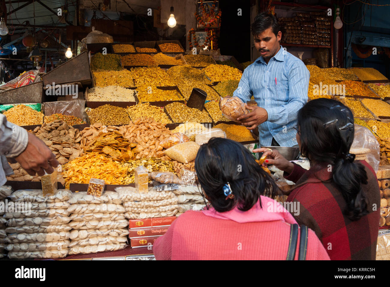 A vendor serves customers at his namkeen (savoury snacks) and sweets stall in Lucknow, India Stock Photo