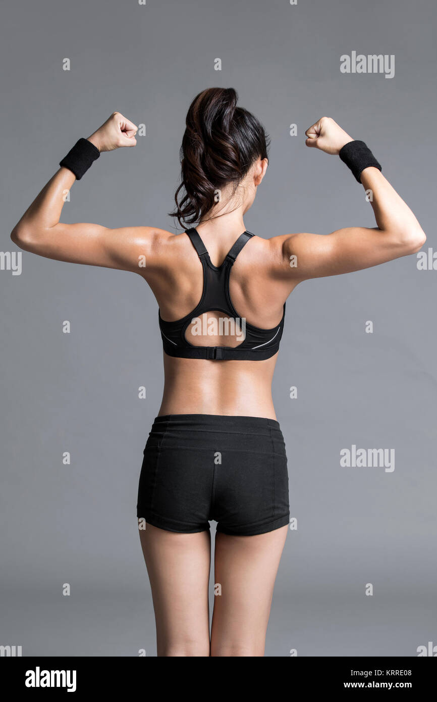 Rear view of young female athlete flexing muscles Stock Photo - Alamy