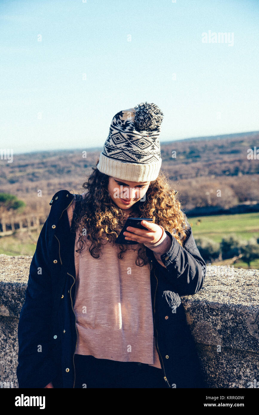 Teenage girl in knit hat texting with cell phone Stock Photo