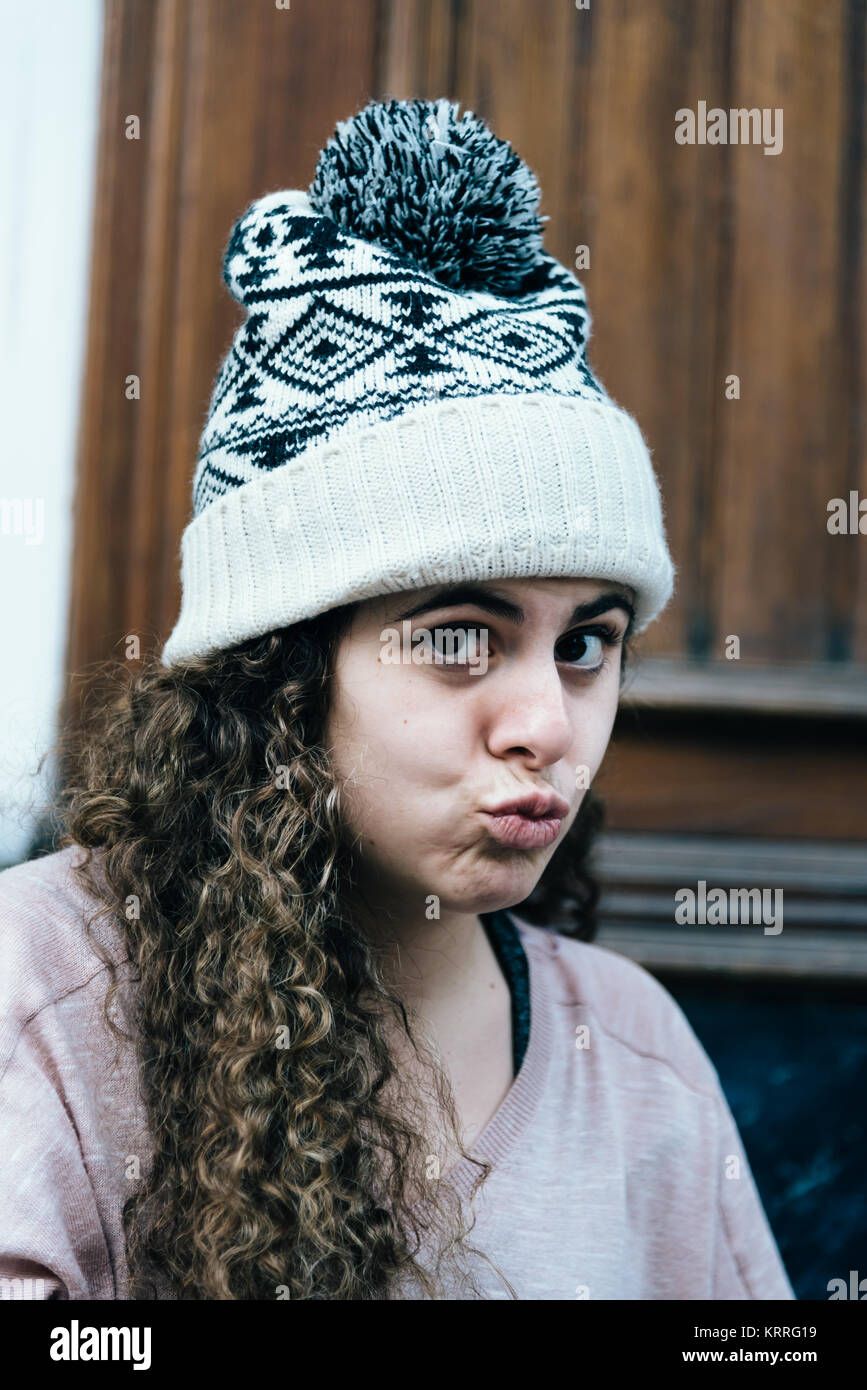 Teenage girl with long and curly hair wearing a knit hat Stock Photo