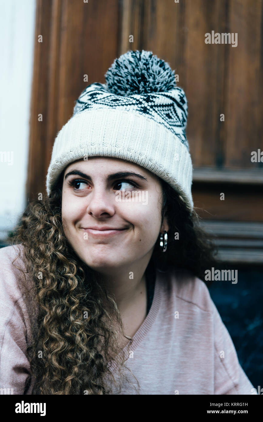 Smiling teenage girl with long and curly hair wearing knit hat Stock Photo