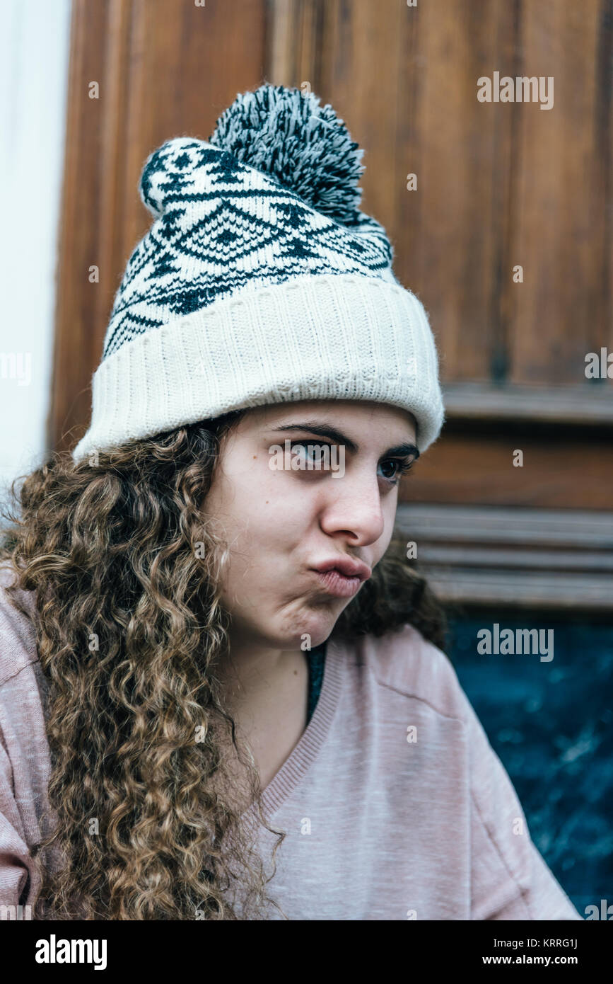 Teenage girl with long and curly hair wearing a knit hat Stock Photo