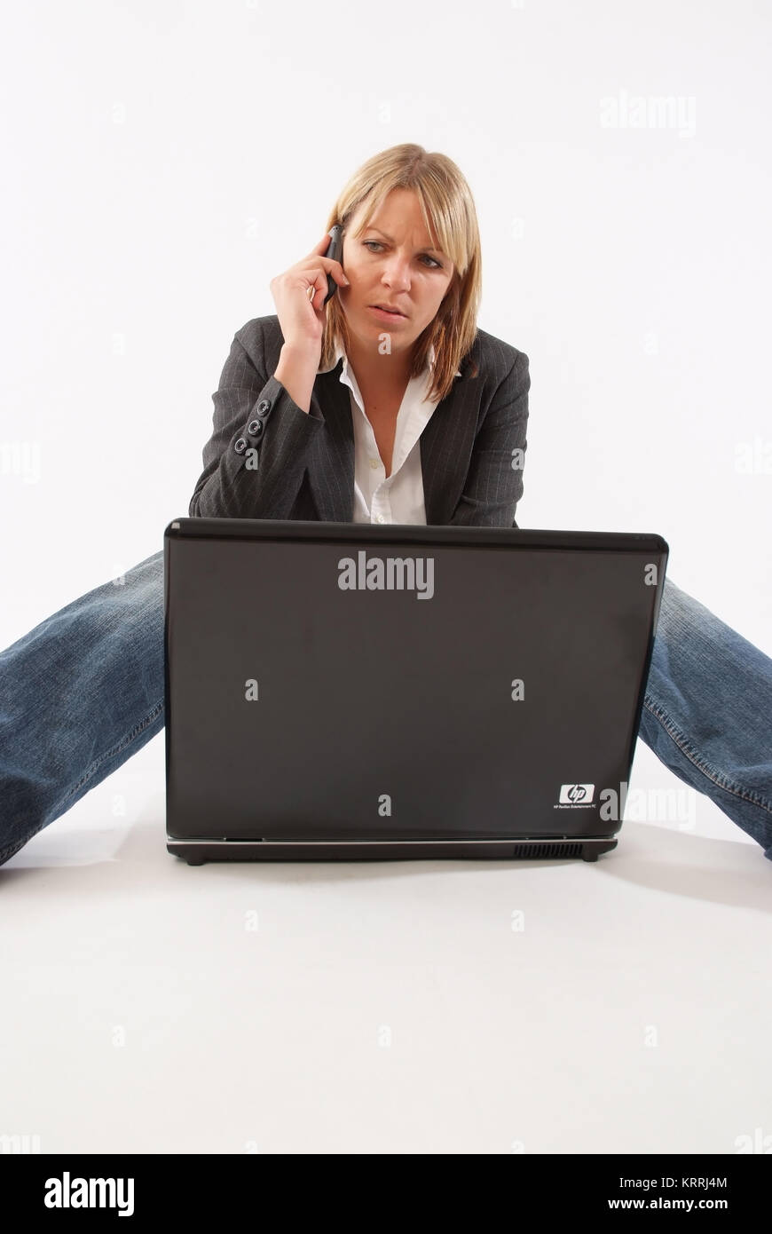 Frau sitzt vor Laptop und telefoniert - woman with mobile using laptop Stock Photo
