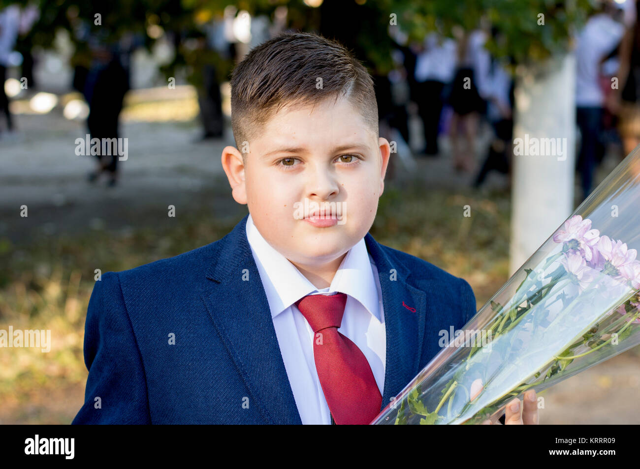 the school student in a claret tie with a bouquet Stock Photo