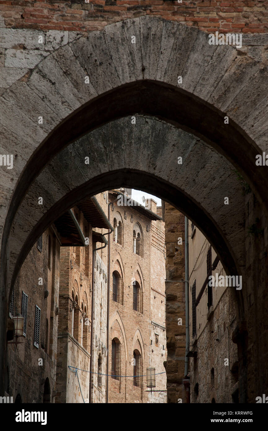 L'arco della Cancelleria on Via San Matteo and medieval Palazzo Vecchio del Podesta in Historic Centre of San Gimignano listed World Heritage by UNESC Stock Photo