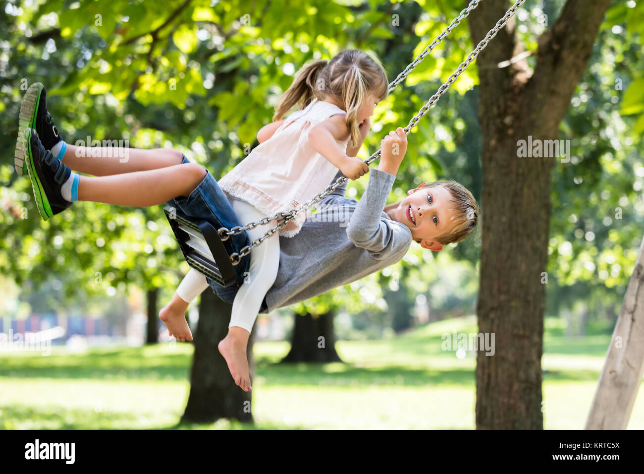 Brother and Sister Enjoying On Swing In The Park Stock Photo - Alamy