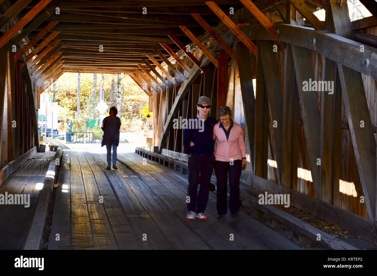 Couple posing on The Poland Covered Bridge, also known as the Junction Covered Bridge over the Lamoille River near Jeffersonville, Vermont, USA Stock Photo