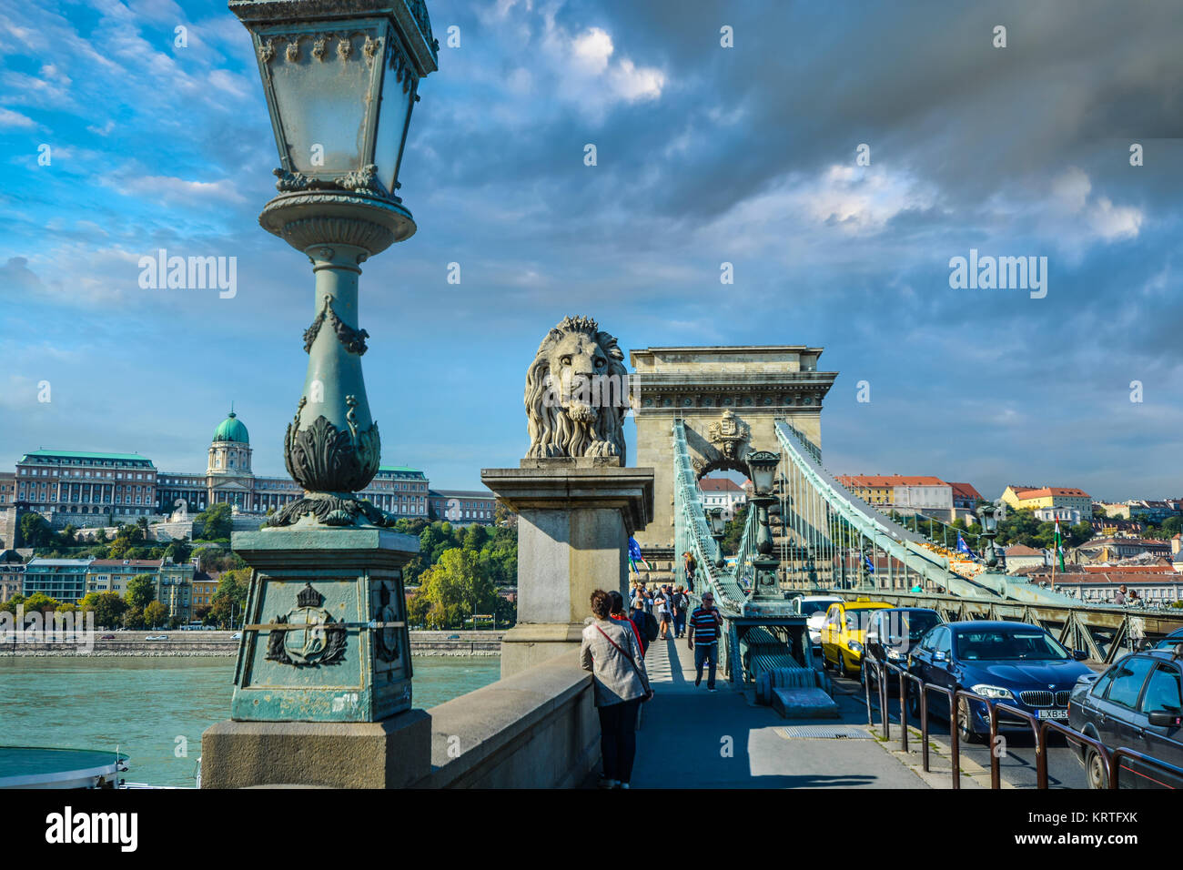 Afternoon on the Chain Bridge over the Danube River in Budapest Hungary with Buda Castle on the hill and the stone lion in the center of the frame Stock Photo