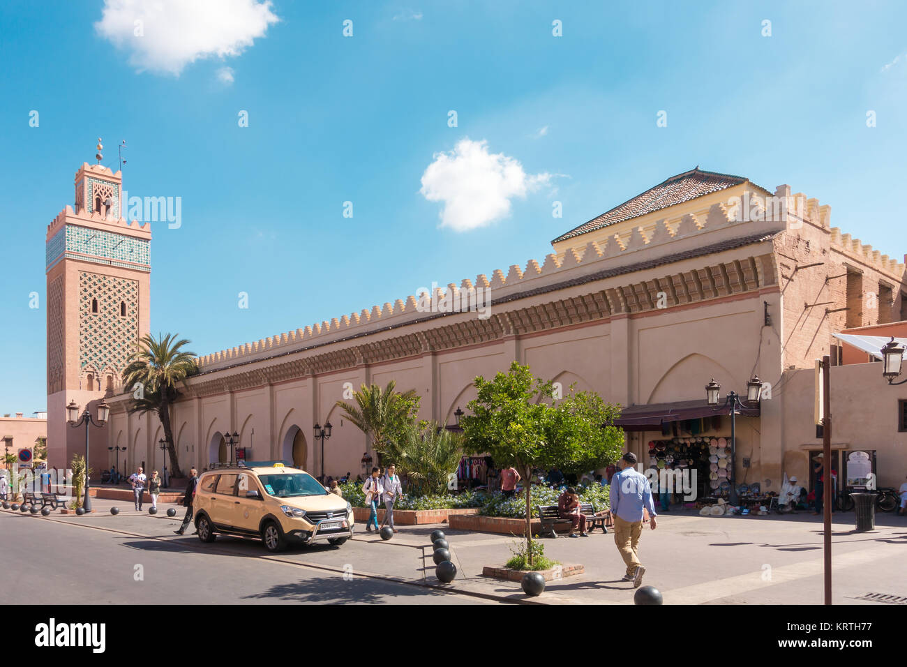 Marrakech, Morocco. 12th May, 2017: Shop owners and a taxi are waiting for customers while people are walking past the Moulay El Yazid Mosque in Marra Stock Photo