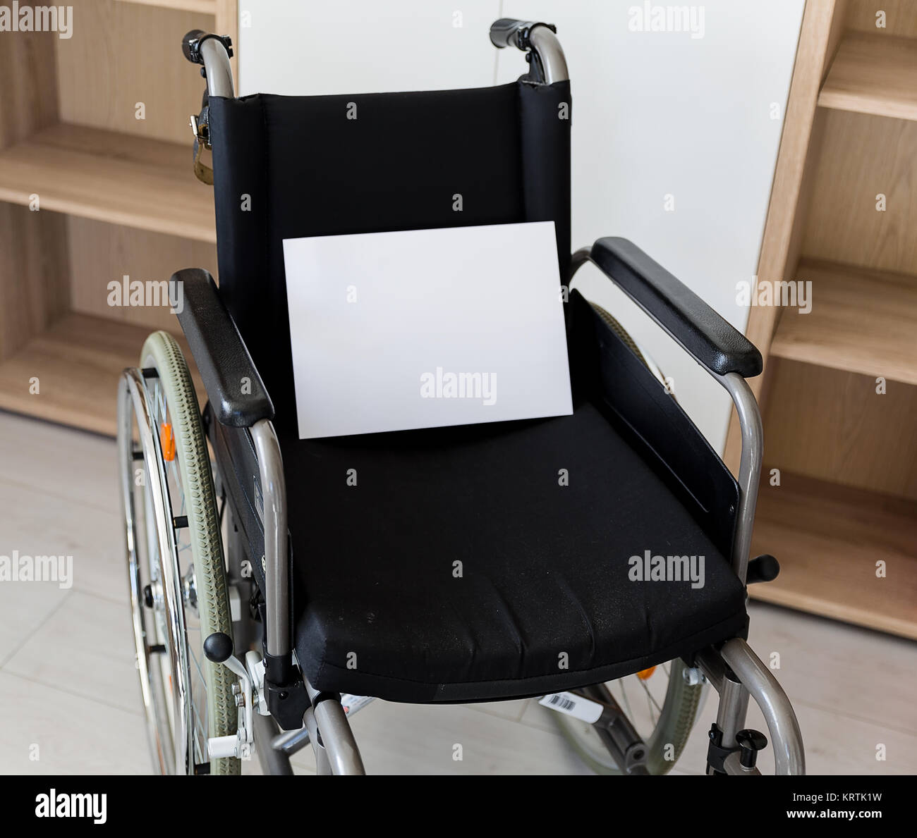 an empty wheelchair faces a wall unit Stock Photo