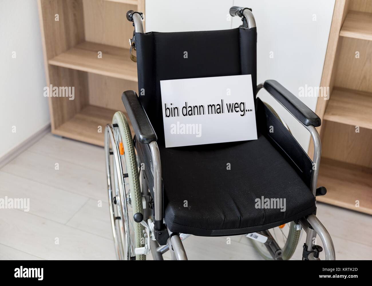 an empty wheelchair faces a wall unit Stock Photo