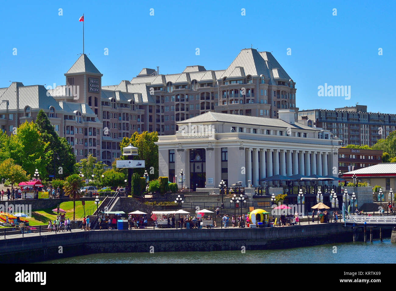 A horizontal view of the waterfront walkway along the inner harbour in Victoria B.C. Canada with iconic buildings in the background. Stock Photo