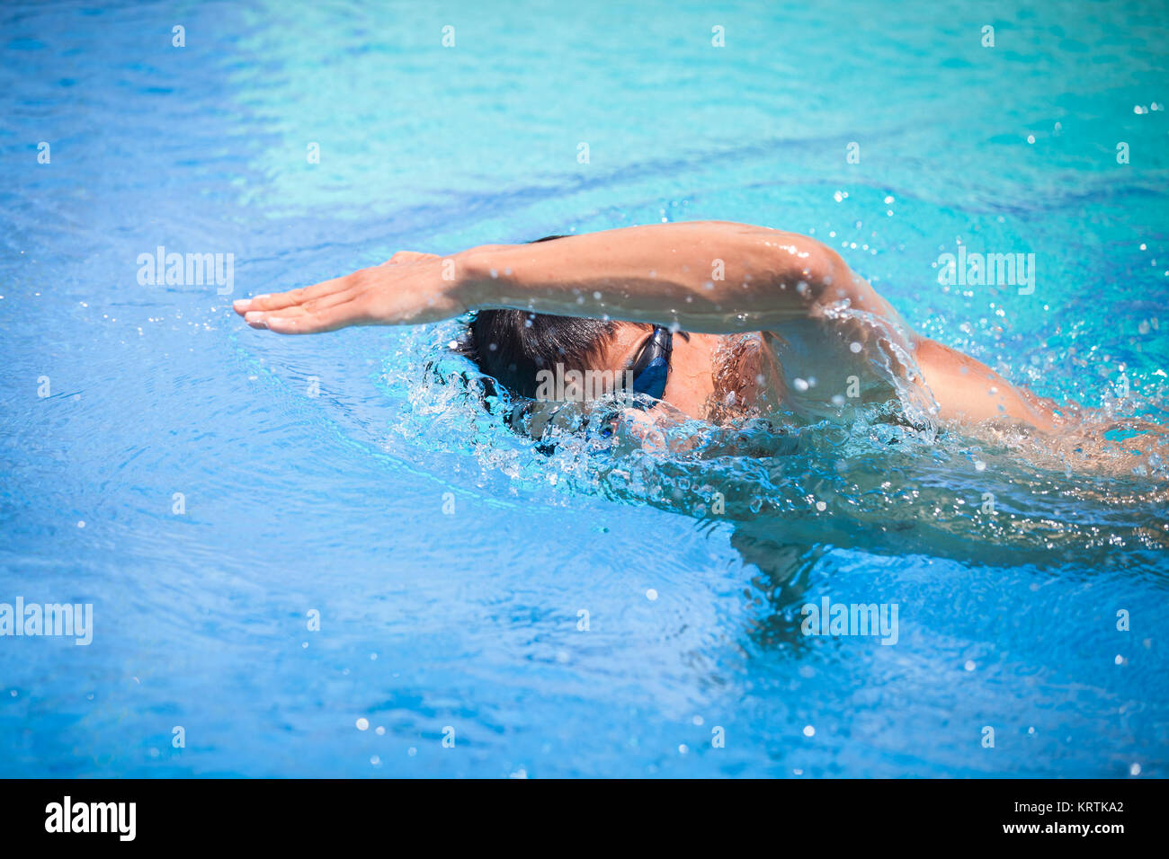 Young man swimming the front crawl in a pool Stock Photo