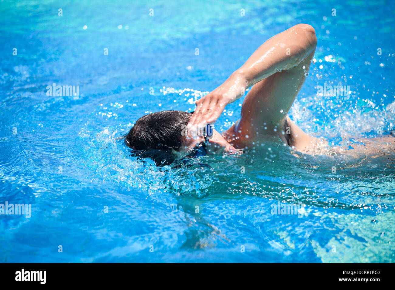 Young man swimming the front crawl in a pool Stock Photo