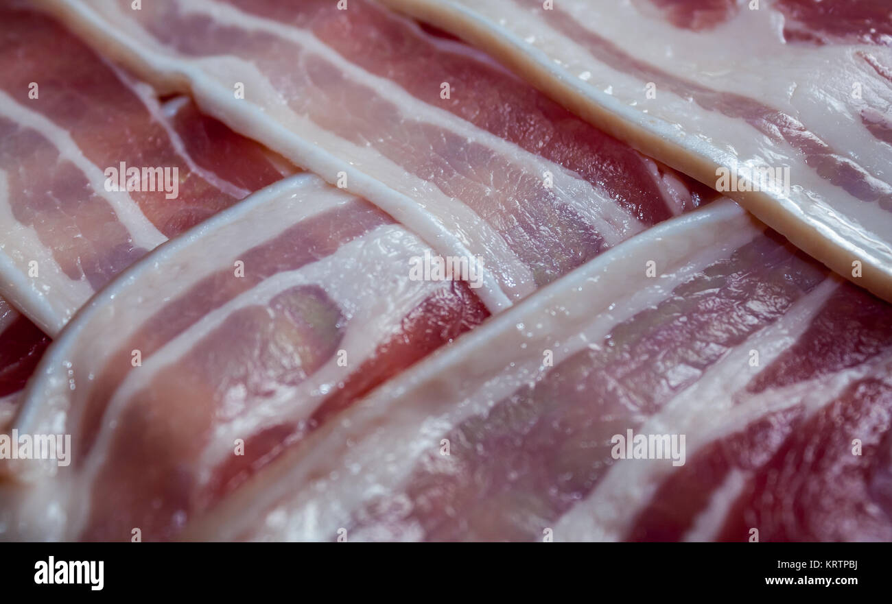 Streaky bacon rashers with rind on arranged in an overlapping pattern Stock Photo