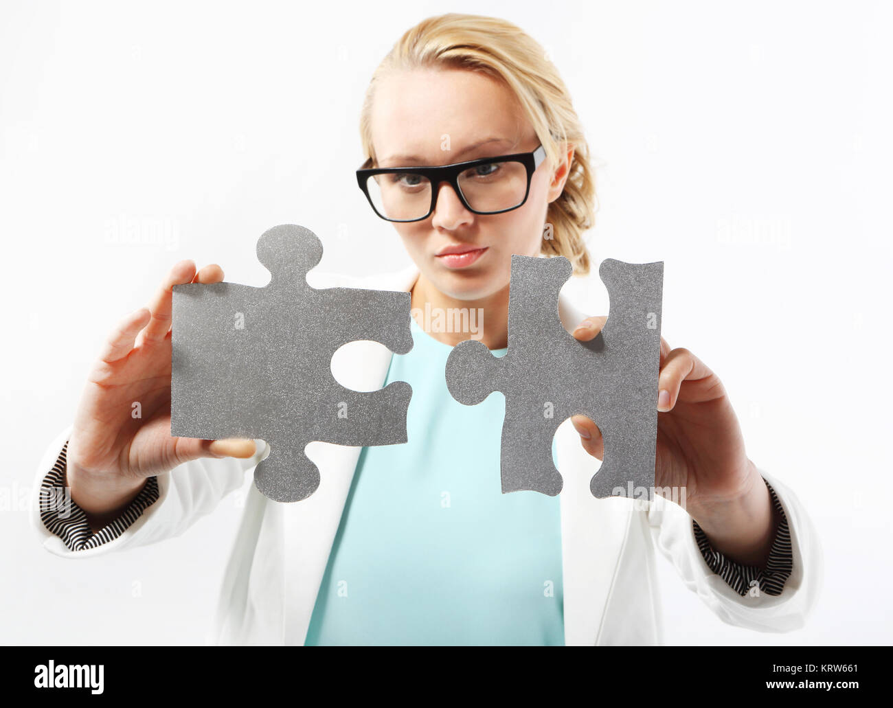 an attractive woman in business attire matches the pieces of the puzzle. Stock Photo