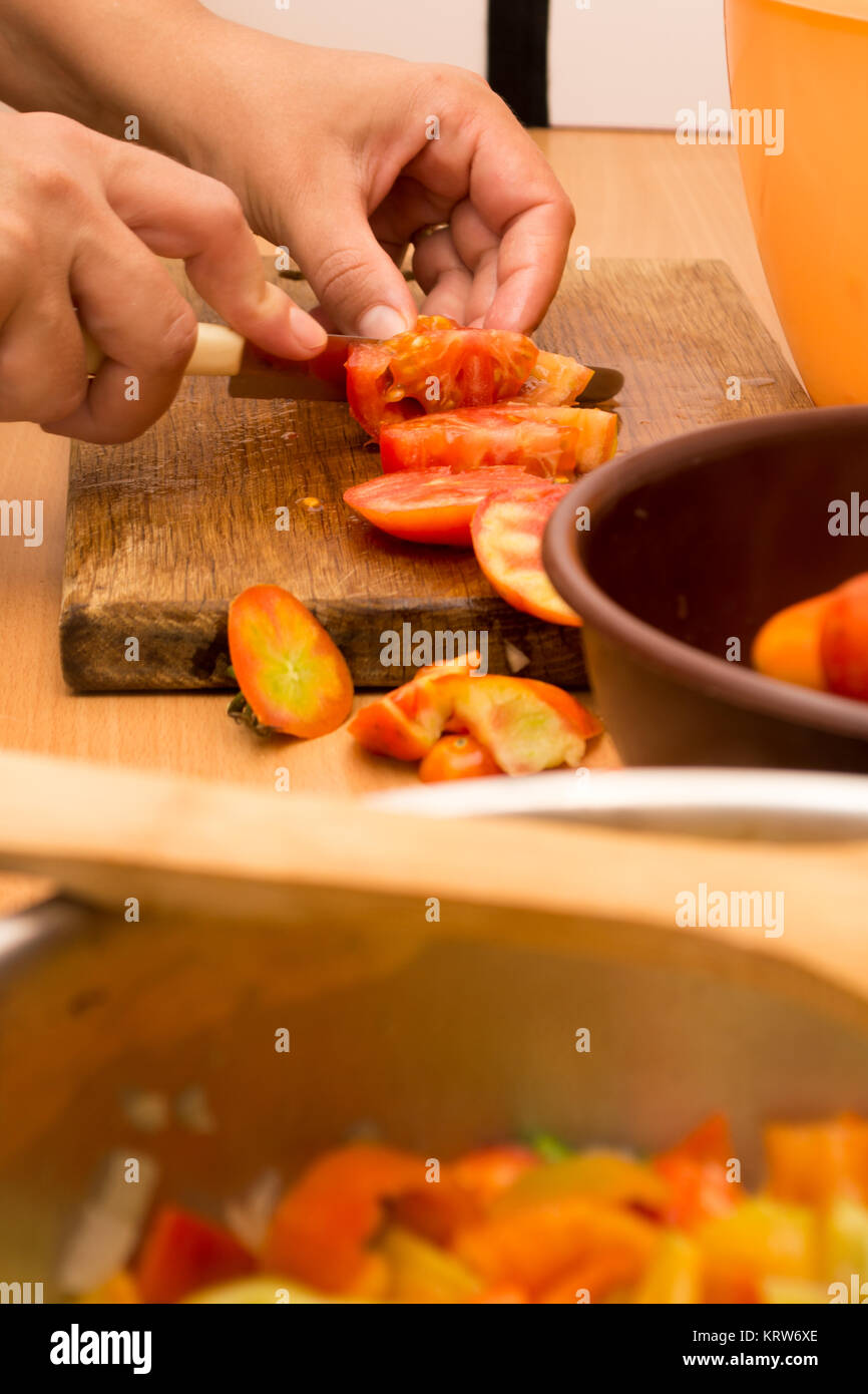 Cutting tomato on a wooden plate Stock Photo