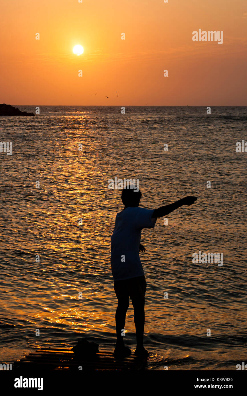 Boy handline fishing at sunset Stock Photo - Alamy