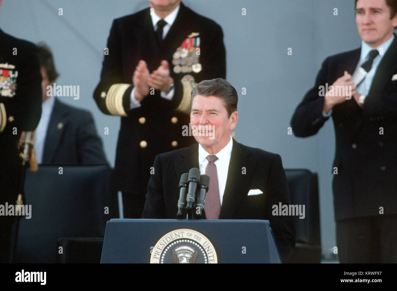 President Ronald Reagan, principal speaker,  addresses the guests attending the recommissioning ceremony for the battleship USS NEW JERSEY (BB-62).  Standing behind him to the right is Secretary of Navy John F. Lehman Jr. Stock Photo