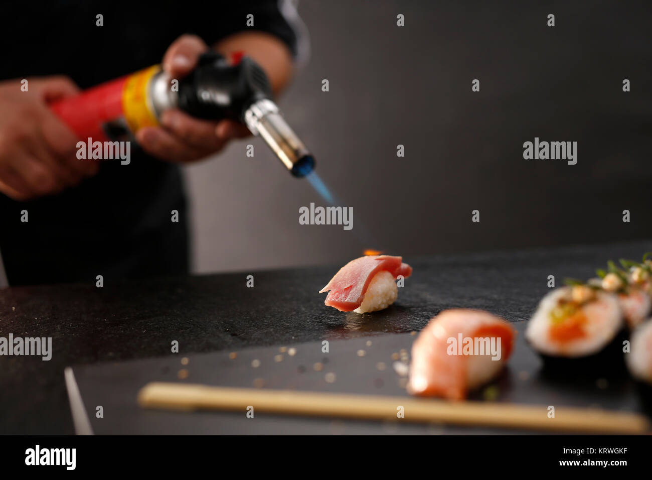 Sushi z surowym Å‚ososiem opalane pÅ‚omieniem. Porcja ryÅ¼u uformowanego w kulkÄ™ przykrytego kawaÅ‚kiem ryby Stock Photo